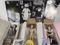 Overview of three dolls in open boxes and four NRFB outfits above