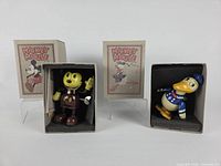 Both tin toys inside foam inserts with their boxes visible