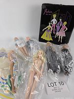 Group shot of five dolls in clear bags and black vinyl Fashion Doll Case