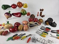 Overview of carved wooden produce, ceramic-handled knives, black pots, fish dish, picks
