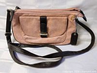 Front view of pink purse with black strap and buckle detail
