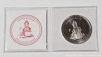 Coin in open clear plastic flip beside red lighthouse insert