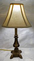 Full view of illuminated metal base table lamp with shade
