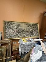Full view of framed tapestry leaning against wall