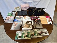 Group shot of handbag, wristlet, two boxes and twelve pantyhose packages on round table