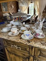 Group shot of all mismatched floral teacups and saucers on countertop