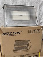 Front view of one LED wall pack on top of box