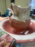 Pitcher inside matching basin with peach glaze, floral fabric in foreground