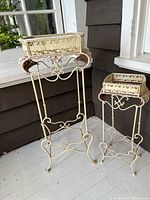 Pair of cream wrought iron and wicker plant stands, tall and short