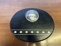 Top view of black Health o meter oval bathroom scale showing dial and shell motif