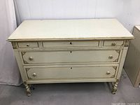 Front view of dresser showing drawers, knobs, gilded accents