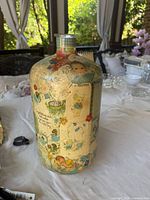 Full view of glass bottle showing overall decoupage collage and shape