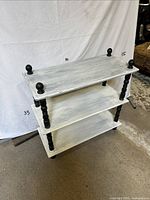 Front view of three-shelf etagere showing white shelves and black spindle legs