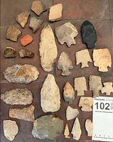 Group view of mixed arrowheads, spear/knife points and shards laid out on tiled surface