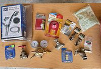 All items laid out on table including shower head box, regulator, valves, spigots and packaged toilet parts