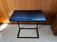 Front view of the black adjustable desk on carpeted floor