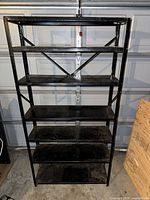 Front view of first black metal shelving unit showing seven shelves and cross-brace