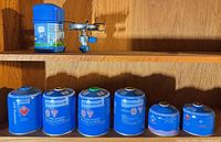 Burner, lantern case and six gas canisters on shelf