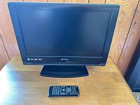 Front view of Emerson LC195EMX TV with remote placed on table