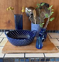 Group shot of all five blue containers with utensils displayed on wooden board
