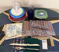 Overview of linens, carving set, sealed sheet, plates, cups, forks, tray, trivet