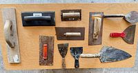 assorted grout floats, trowels and scrapers laid out on table