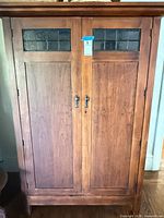 Closed front view showing leaded glass panels and door pulls