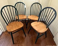 Four green spindle-back chairs grouped together, front angle