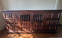 Front view showing full credenza with carved panels and spindle doors