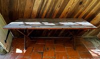 Full view of rectangular slatted wood outdoor table against wall