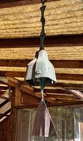 Full view of bronze wind bell hanging from bracket