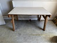 Full view of rectangular table with white laminate top and natural wood legs