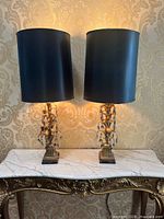 Both lamps with shades illuminated on a marble-top console