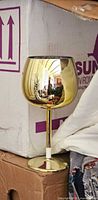 Single gold plastic goblet displayed against boxes