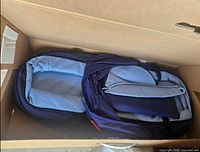Bassinet inside box, navy exterior and light blue interior visible