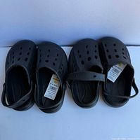 Top view of two pairs of black slip-on clogs