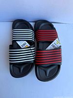 Top view of two sandals showing white and red striped straps, tags visible