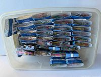Plastic bin holding multiple boxed packs of colorful paper clips