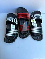 Three pairs of slide sandals with tags visible