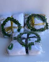 Three packaged milestone blankets with wreaths visible