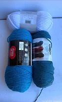 Three skeins showing brands Lion Brand, Caron Simply Soft, Red Heart