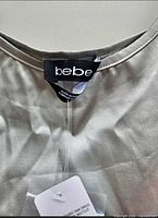 Close-up of bebe brand tag on neckline of silver dress