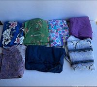 Ten folded scrub garments laid out showing prints and colours