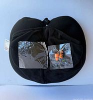 front view of black travel pillow with two small sealed accessory packs