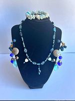 Full view of necklace on stand with bracelet atop and earrings hanging at sides