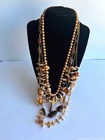 all four necklaces layered on bust showing materials and pendant