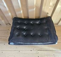 Top view showing black leather button-tufted cushion
