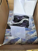 Open carton showing boxed sneakers and one displayed pair inside box