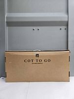Closed cardboard box labeled gb Cot To Go Future Perfect