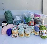 Front view showing labeled Peaches & Creme skeins, DIYarn, teal cone and loose skeins